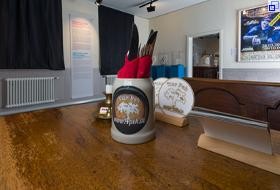 Ausstellungsraum: Ein Wirtshaustisch, auf dem ein Maßkrug mit Besteck und Servietten steht.