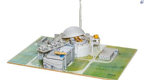 Papiermodell eines Atomkraftwerks auf grünem Untergrund. Die Dächer des Reaktorgebäudes und des Maschinenhauses sind geöffnet.