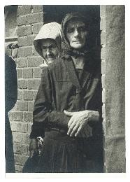 Zwei Frauen mit Kopftüchern stehen in einem Eingang in einer Ziegelmauer