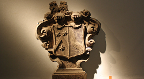 Behauener Stein in Form eines verzierten Wappens.