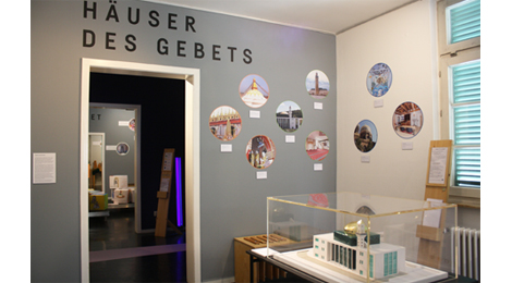 Ausstellungsraum mit der Beschriftung "Häuser des Gebets". Ein Modell der Esslinger Moschee steht auf einem Tisch.