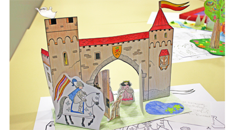 Ein Schloss mit großem Tor und zwei Türmen, das aus Papier gebastelt ist.