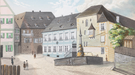 Bild vom Hafenmarkt mit mehreren Gebäuden, darunter die Gebäude Hafenmarkt 7 und 9 mit dem mittelalterlichen Wohnturm, davor ein Brunnen auf dem Platz.