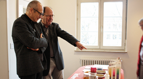 Zwei Männer betrachten Ausstellungsobjekte auf einem Podest. Einer deutet auf ein Objekt.