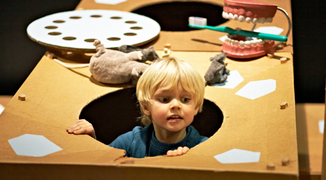 Foto: Kind in der Ausstellung, es sieht aus einem Loch heraus. Foto: wamiki/Jens Steingässer (Ausschnitt)
