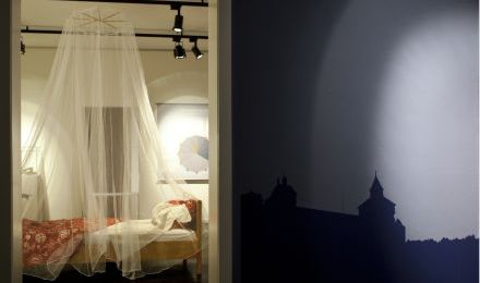 Ausstellungsraum mit Bett mit Moskito-Netz.