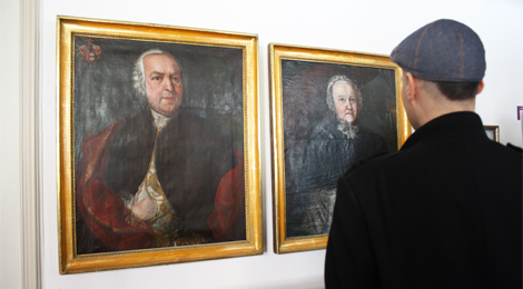 Ein Besucher betrachtet zwei Porträtgemälde.
