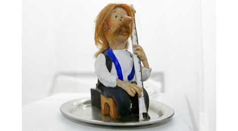 Eine kleine Figurine, die Eberhard Weber in typischer Haltung darstellt. Statt des Elektrobasses hält sie ein Thermometer.