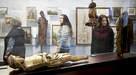 Ausstellungsraum im Stadtmuseum: Besucherinnen betrachten religiöse Skulpturen und Gemälde von Kirchen