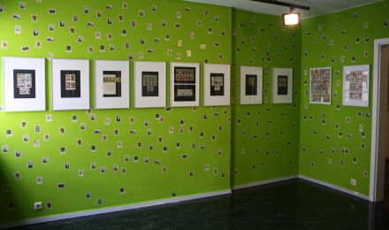 Ausstellungsraum: An den Wänden hängen Bilderrahmen mit Zusammenstellungen von kleinen Reklamen. Die Wand ist mit Reproduktionen von Reklamemarken übersät.