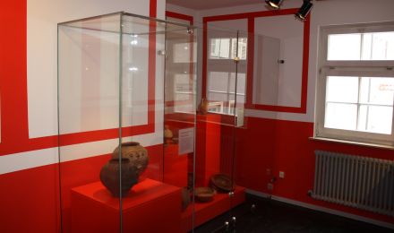 Ausstellungsraum Römerzeit: In einer Vitrine stehen zwei kugelförmige Vorratsgefäße mit plastischen Gesichtsdarstellungen.
