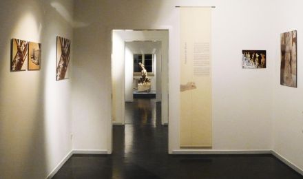 Ausstellungsraum mit Fotografien von Wasserspeiern. Im Hintergrund ist ein echter Wasserspeier ausgestellt.