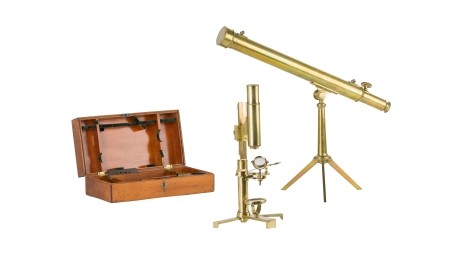 Aufgestellte naturwissenschaftliche Instrumente aus Messing: Tischfernrohr und Mikroskop, daneben die Aufbewahrungskiste aus Holz.