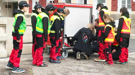 Die Kinder der Feuerflitzer beobachten, wie ein Gerätewagen geöffnet wird.