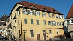 Das Stadtmuseum im Gelben Haus: Sichtbar ist ein großes barockes Wohnhaus mit vielen Fenstern, seitlich davon ein mittelalterlicher Wohnturm mit Erker.
