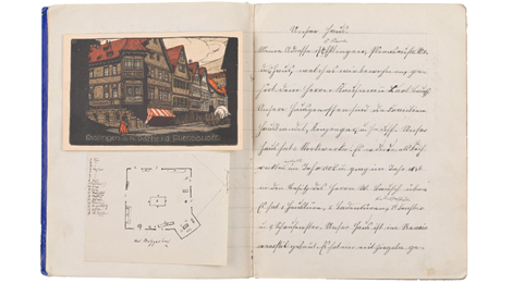 Aufgeschlagenes Buch mit eingeklebter Postkarte, Grundrissplan eines Hauses sowie fein säuberlicher Handschrift.