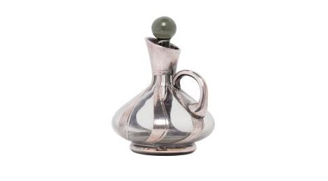 Eine kleine Karaffe aus Glas Ihre schwungvolle Form ist von Silberstreifen umfangen. Auch der Henkel ist aus Silber, der kugelförmige Stöpsel aus Glas. 