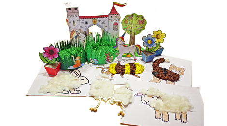 Viele Bastelarbeiten aus Kartonmodellbogen stehen auf einem Tisch. Darunter Blumentöpfe, ein Baum, Schafe, ein Hase und so weiter.